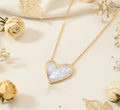 Heart-shaped pendant necklace on a light background with flowers and leaves