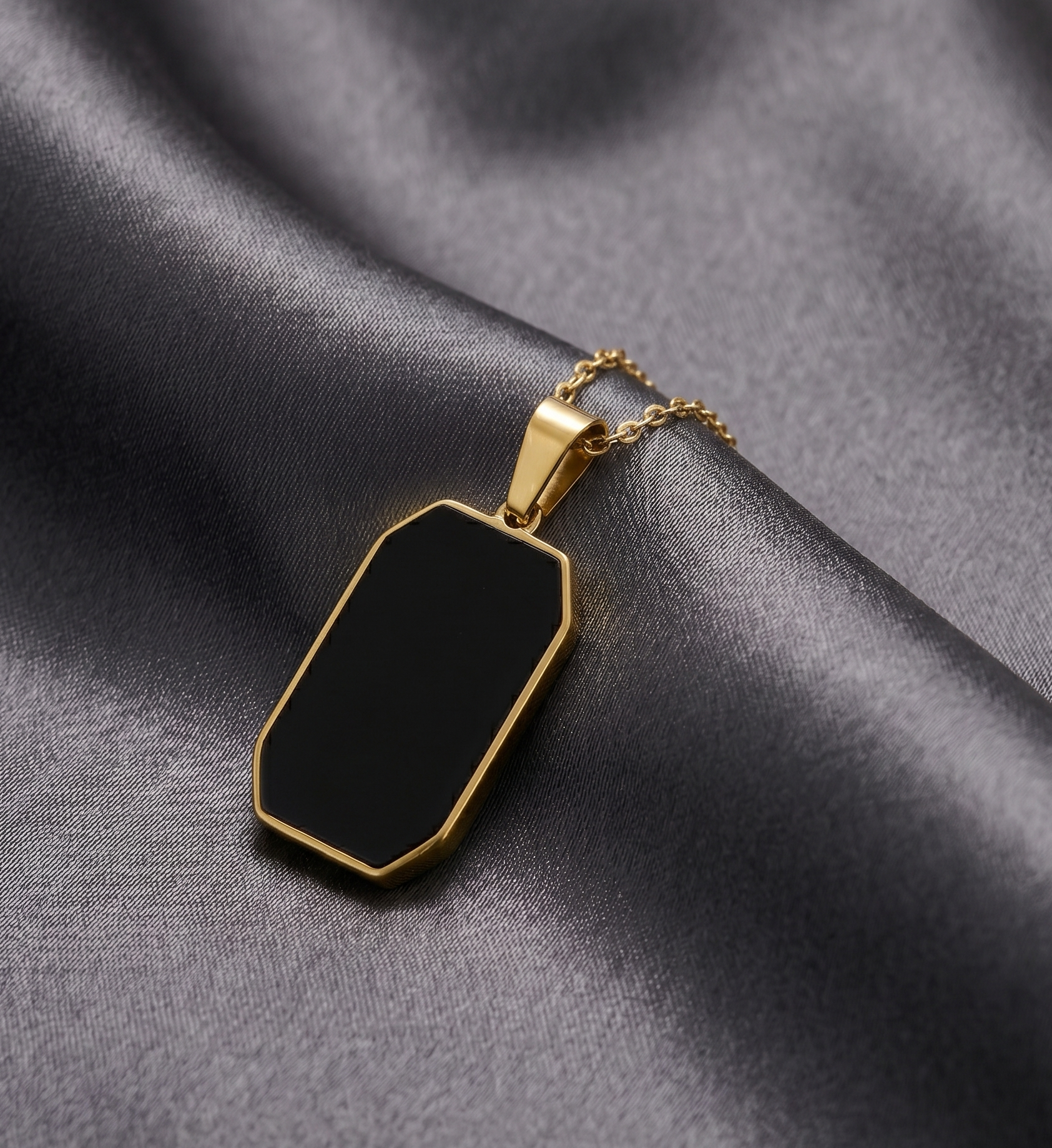 Gold necklace with a black pendant on a gray fabric background
