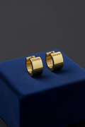Gold hoop earrings on a blue velvet stand against a dark background
