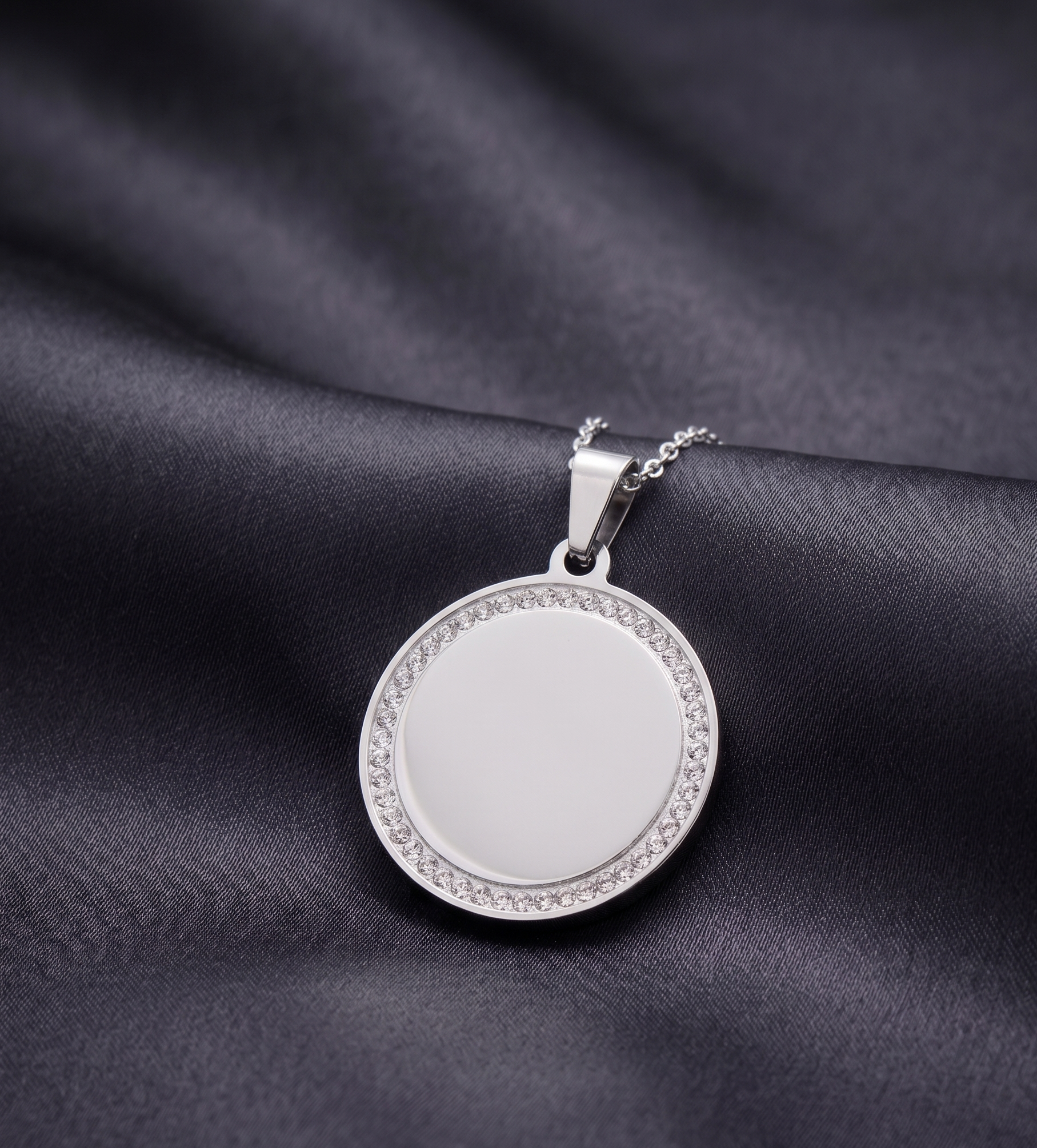 Silver pendant with a circular design on a dark fabric background