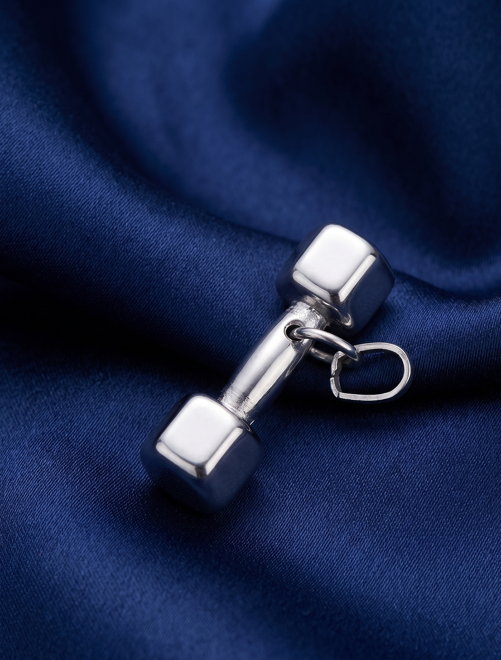 Silver dumbbell-shaped earring on a blue fabric background