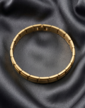 Gold bracelet on a dark gray fabric background