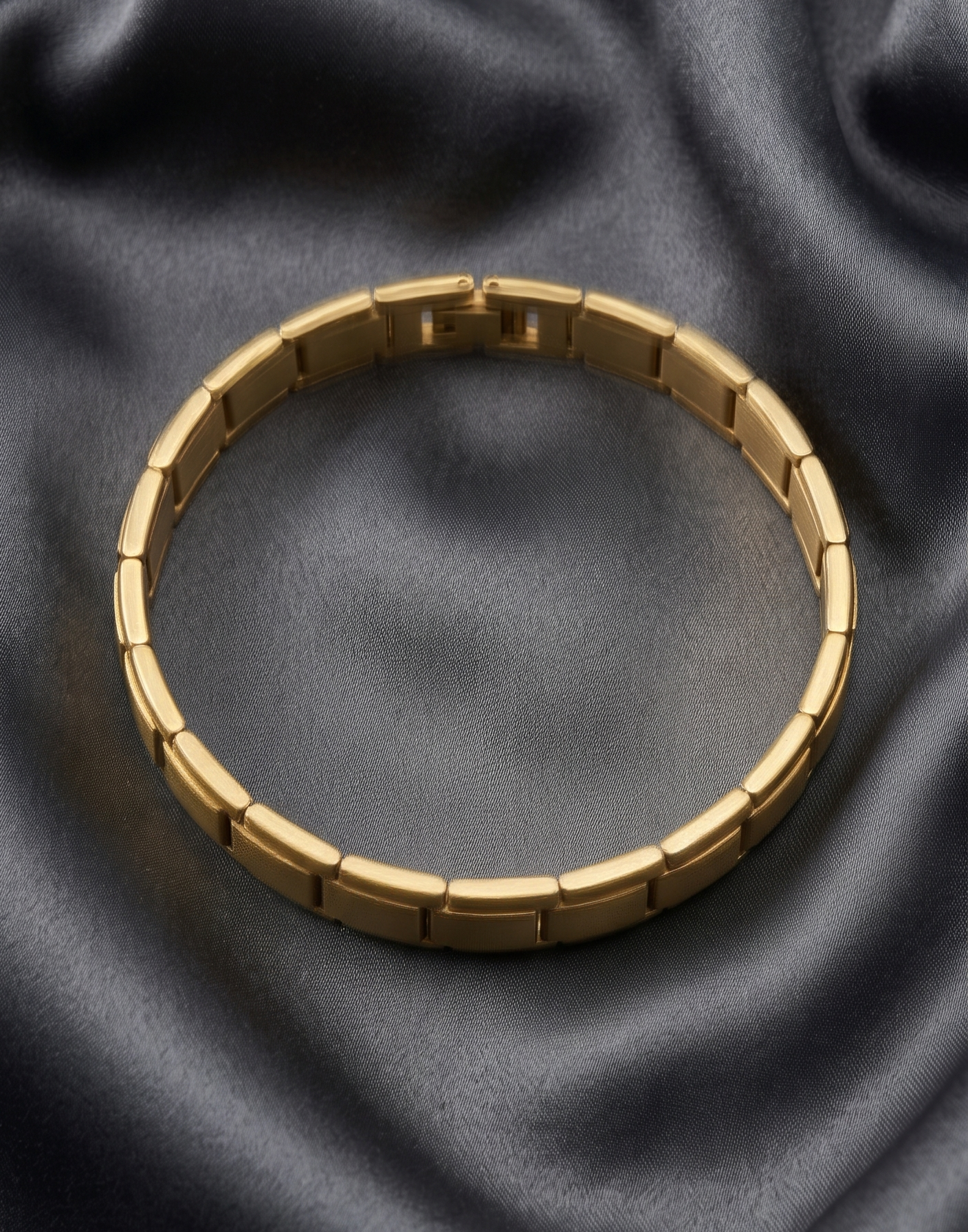 Gold bracelet on a dark gray fabric background