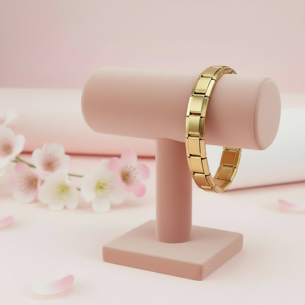 Gold bracelet on a pink stand with a soft pink background and flowers.