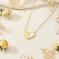 Gold heart-shaped pendant necklace on a soft beige background