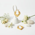 Gold hoop earrings with geometric design on a white background