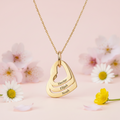 Gold necklace with engraved names on a pink background with flowers