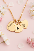 Gold necklace with heart-shaped charms engraved with names on a white background