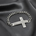 Silver chain bracelet with a cross pendant on a black surface