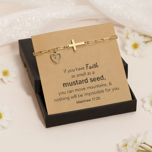 Gold bracelet with heart and cross charms on a cardboard card with a quote, on a light background