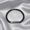 Black chain bracelet with a silver tag on a light gray background