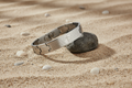 Metallic bracelet with engraved text and cross design on a rock, on sandy  background
