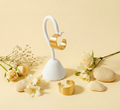 Gold earrings on a white stand with flowers and stones on a beige background