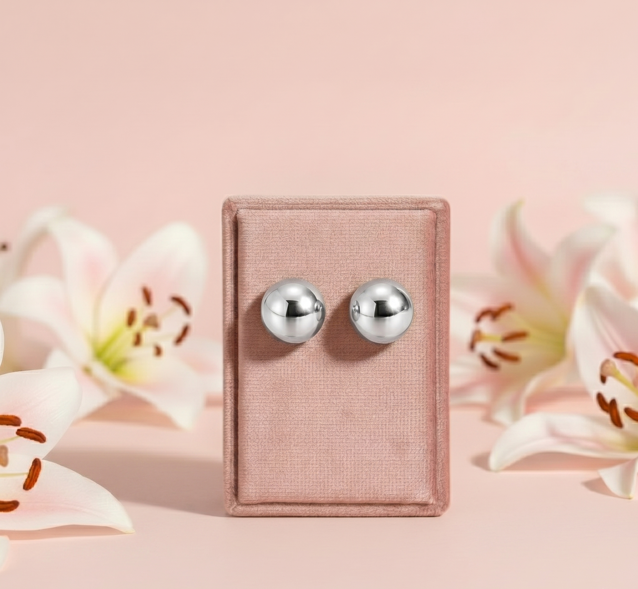 Pair of silver round earrings on a pink card with flowers in the background