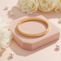 Gold bracelet on a yellow stand with white flowers and pearls